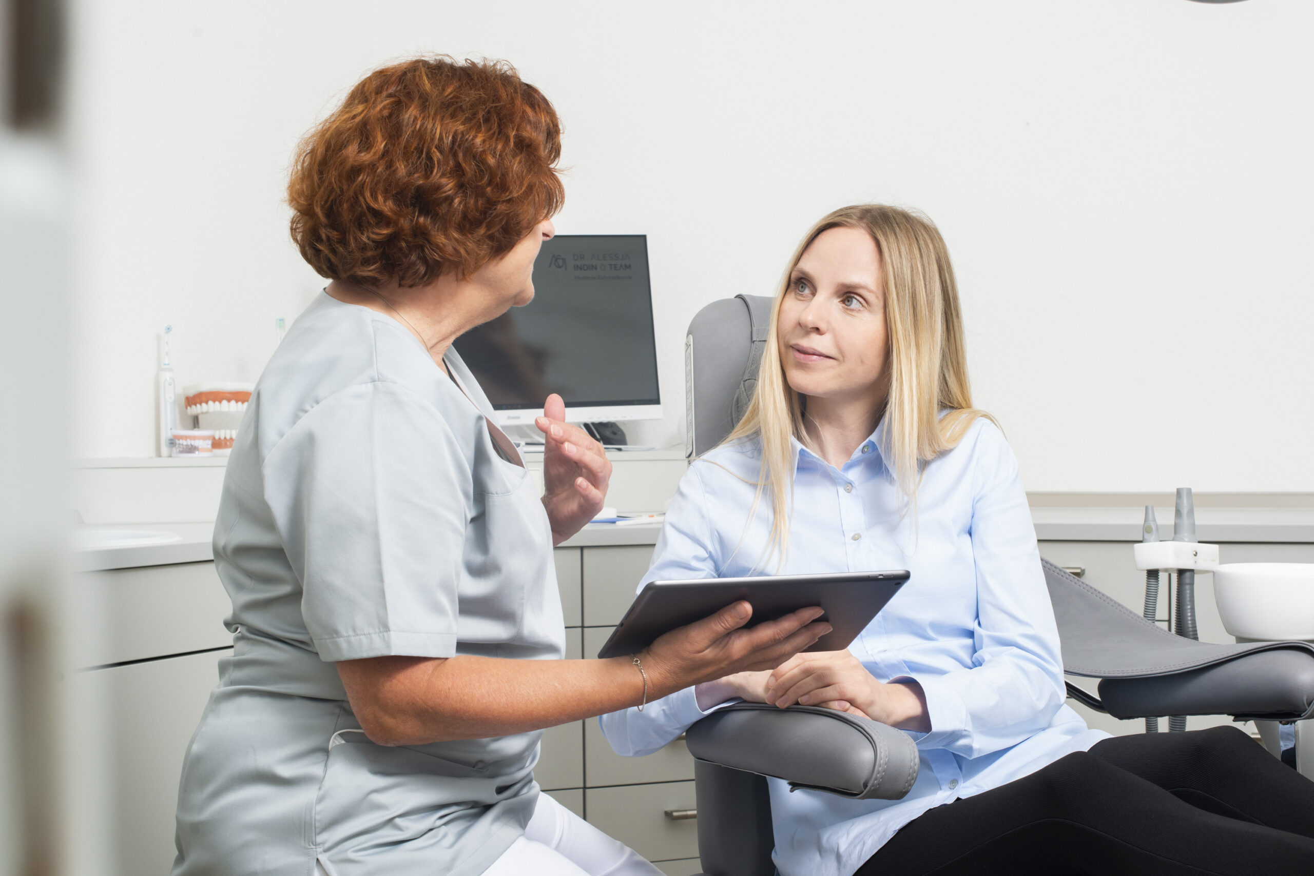 Zahnärztin und Patientin besprechen den digitalen Behandlungsplan der Alignertherapie am Tablet